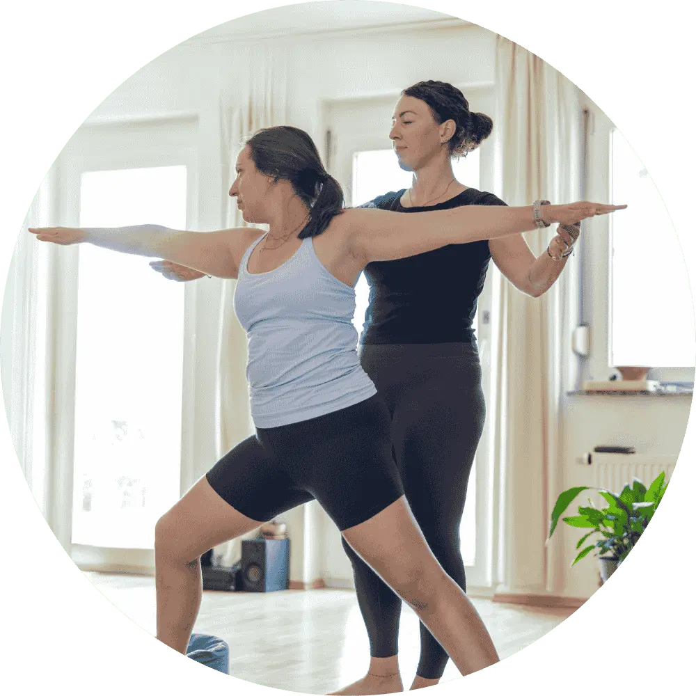 Yogalehrerin, die einer Schülerin bei der korrekten Ausführung einer Asana unterstützt