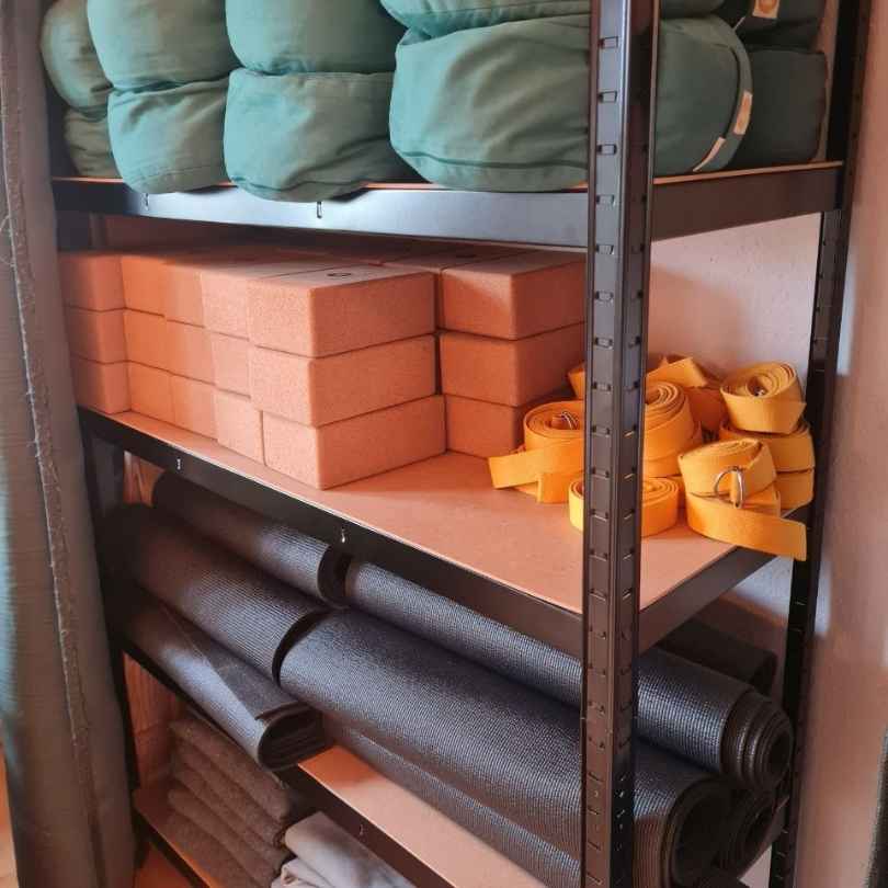 Matten, Blöcke, Kissen, Gurte und Decken in einem Regal im Yogastudio